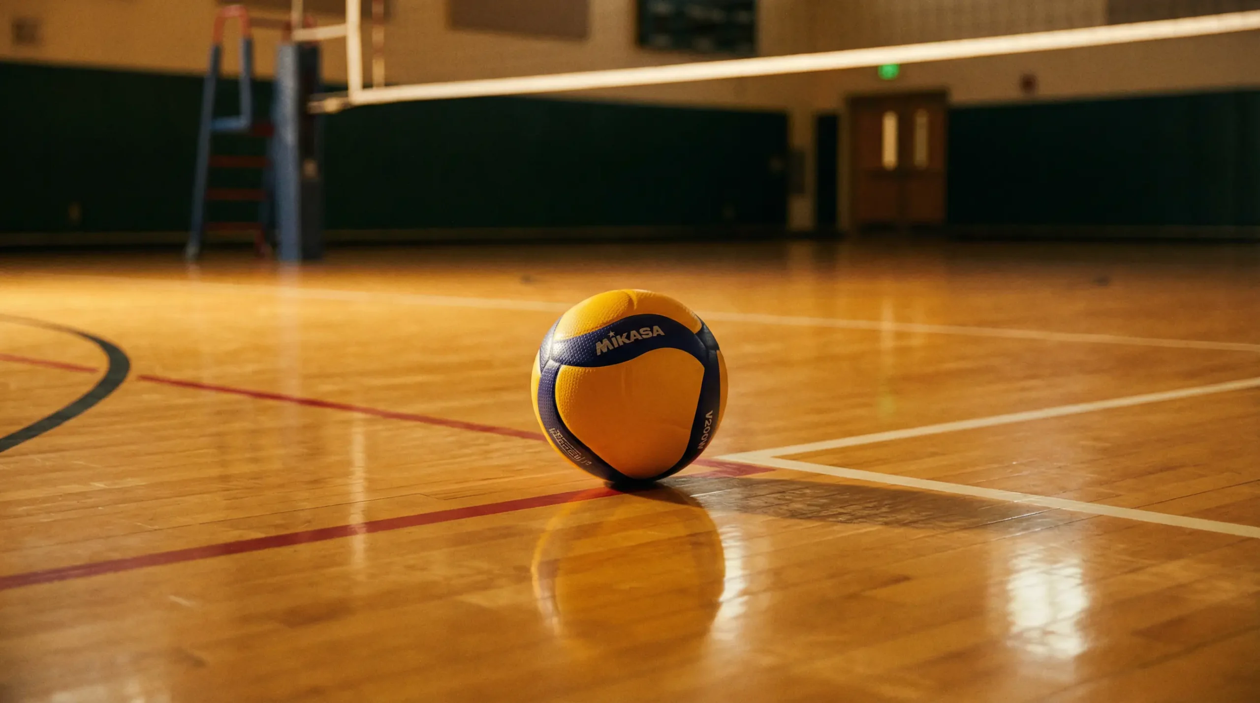 Nahaufnahme eines Volleyballs auf einem Hallenfeldboden mit Netz im Hintergrund